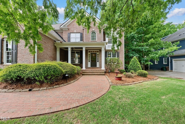 view of front facade featuring brick siding, a front yard, and a porch