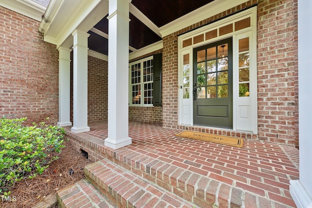 property entrance with a porch and brick siding