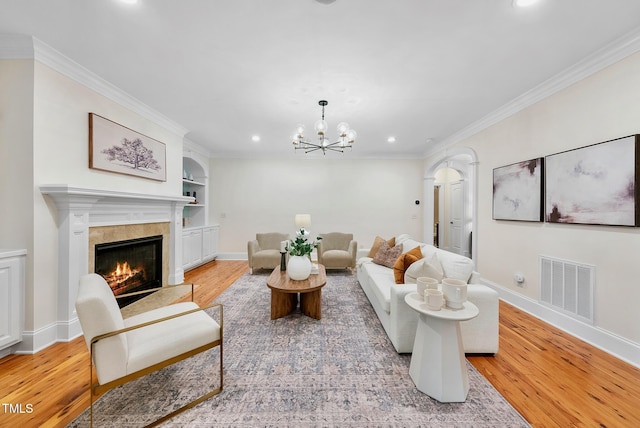 living area featuring recessed lighting, light wood-style floors, baseboards, a fireplace, and crown molding