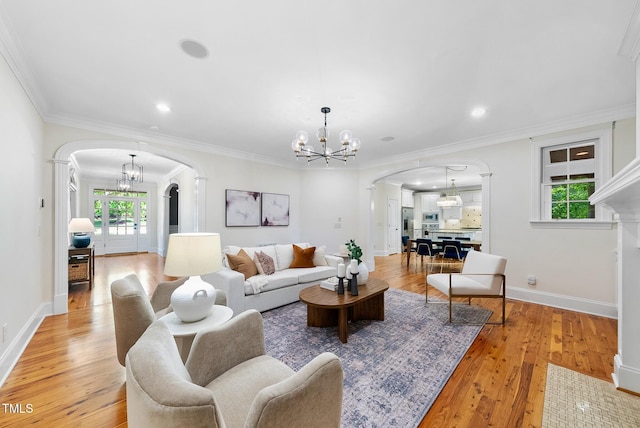 living room featuring arched walkways, a chandelier, light wood-style floors, recessed lighting, and crown molding