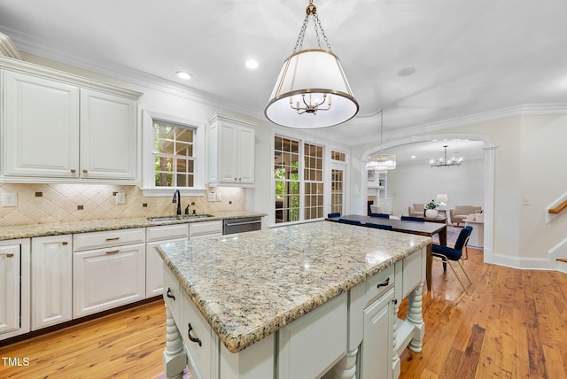 kitchen featuring a chandelier, a sink, dishwasher, light wood-type flooring, and tasteful backsplash