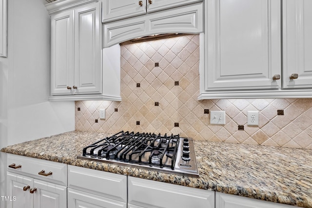 kitchen with stainless steel gas stovetop, white cabinets, and decorative backsplash