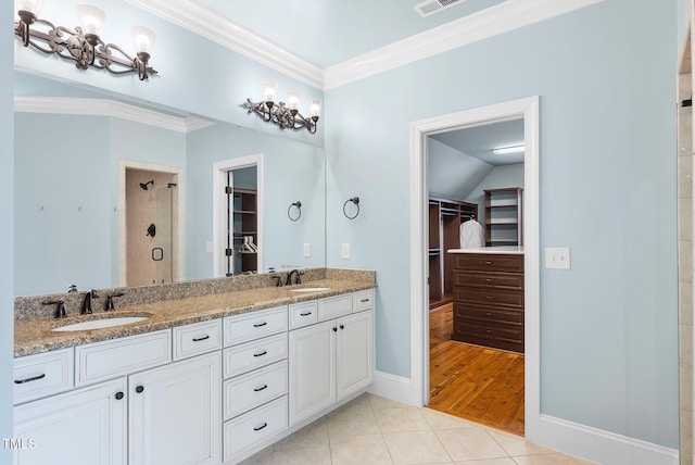 bathroom featuring a shower stall, tile patterned flooring, crown molding, a walk in closet, and double vanity