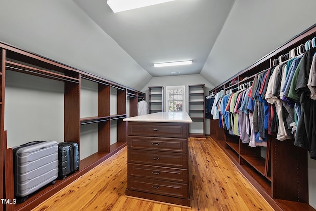 walk in closet with light wood finished floors, vaulted ceiling, and a skylight