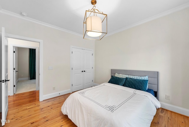 bedroom featuring ornamental molding, light wood-type flooring, baseboards, and a closet