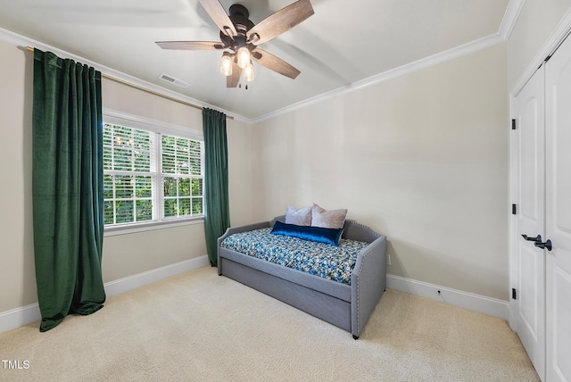 carpeted bedroom with crown molding, baseboards, ceiling fan, and a closet