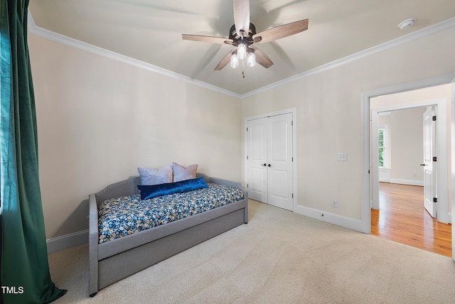 bedroom with baseboards, crown molding, carpet floors, ceiling fan, and a closet