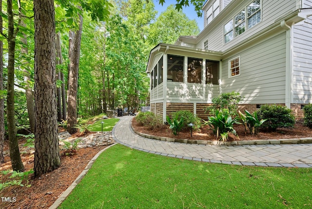 view of home's exterior featuring a sunroom and a yard