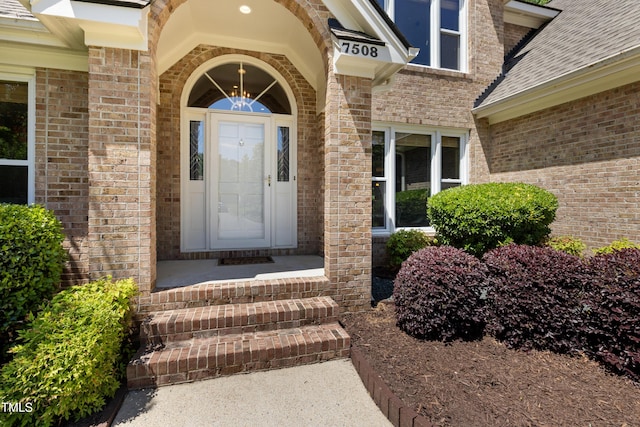 property entrance with brick siding and a shingled roof