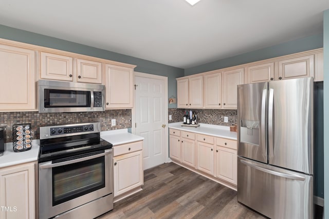 kitchen featuring dark wood-style flooring, appliances with stainless steel finishes, light countertops, cream cabinetry, and tasteful backsplash