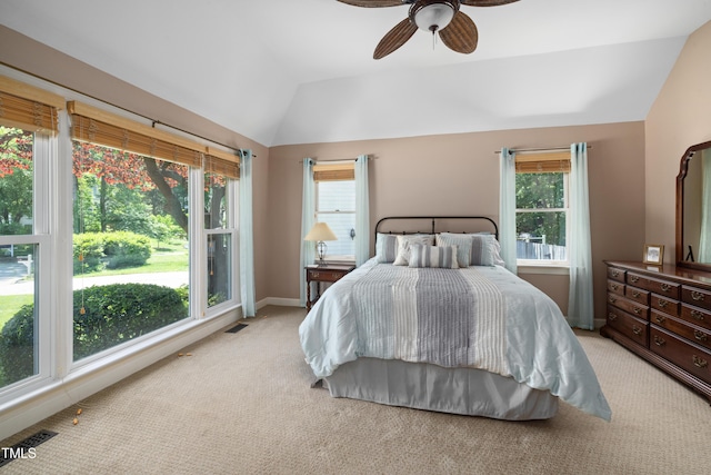 bedroom featuring light colored carpet, lofted ceiling, visible vents, and multiple windows