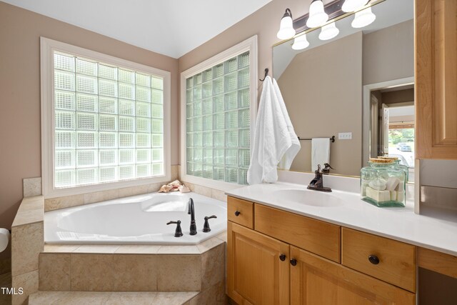 bathroom with a garden tub, a healthy amount of sunlight, and vanity