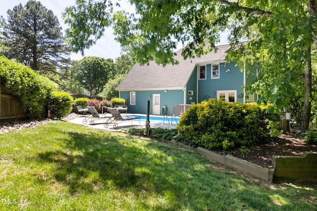 back of property featuring fence, roof with shingles, a fenced in pool, a lawn, and a patio
