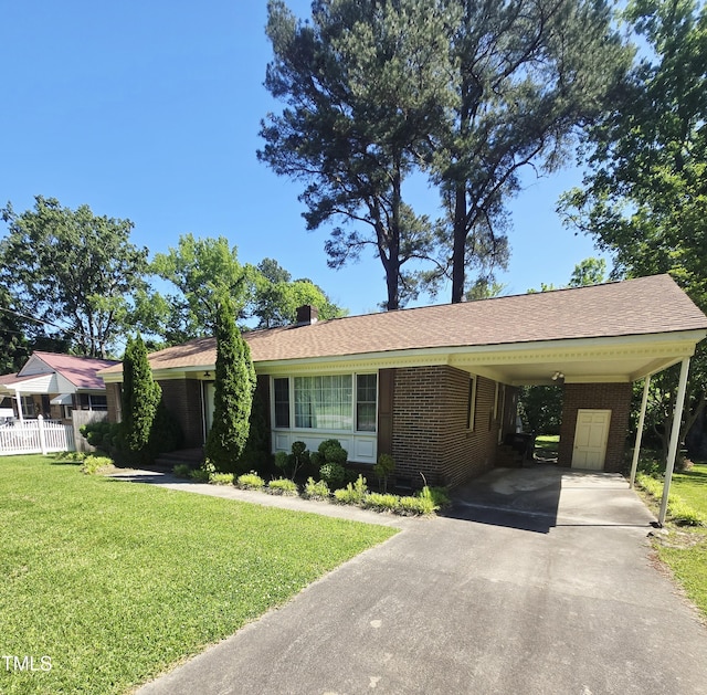ranch-style home with asphalt driveway, brick siding, a carport, and a chimney