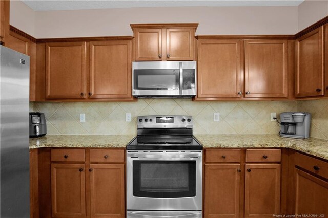 4258 Cherry Hill Ln, Fayetteville, NC 28312 - kitchen featuring light stone counters, decorative backsplash, appliances with stainless steel finishes, and brown cabinets