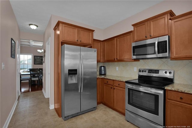 4258 Cherry Hill Ln, Fayetteville, NC 28312 - kitchen featuring backsplash, brown cabinets, light stone counters, a notable chandelier, and stainless steel appliances