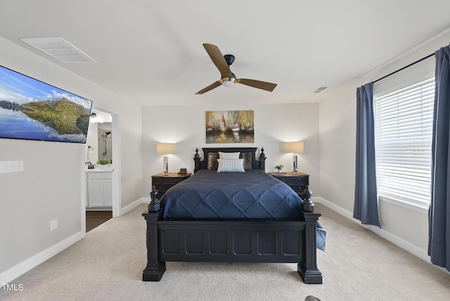 bedroom featuring visible vents, baseboards, ensuite bath, and light colored carpet