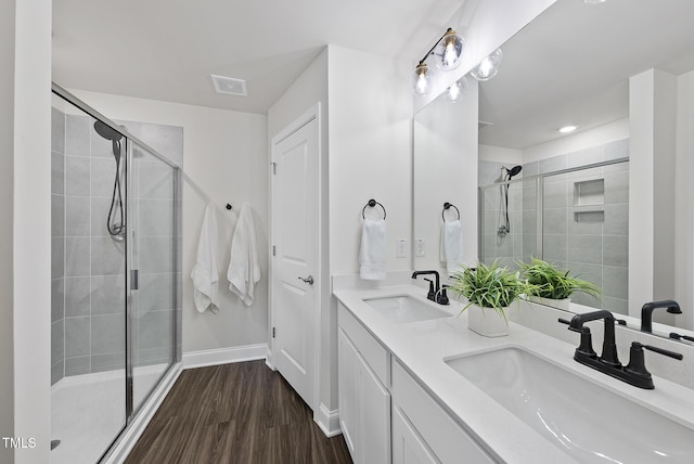 full bath with double vanity, a sink, wood finished floors, and a shower stall