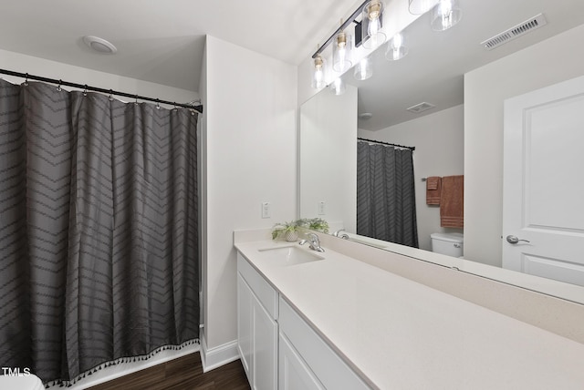 bathroom featuring vanity, toilet, wood finished floors, and visible vents