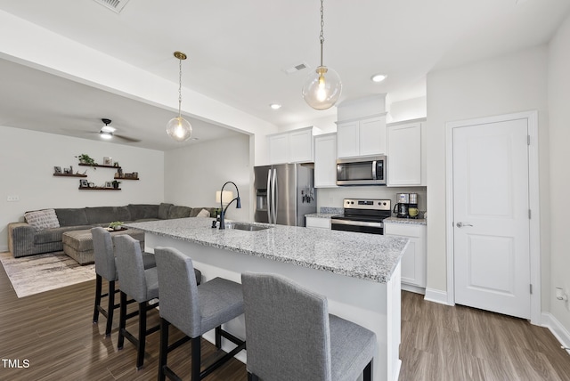 kitchen with a breakfast bar area, visible vents, appliances with stainless steel finishes, a sink, and an island with sink