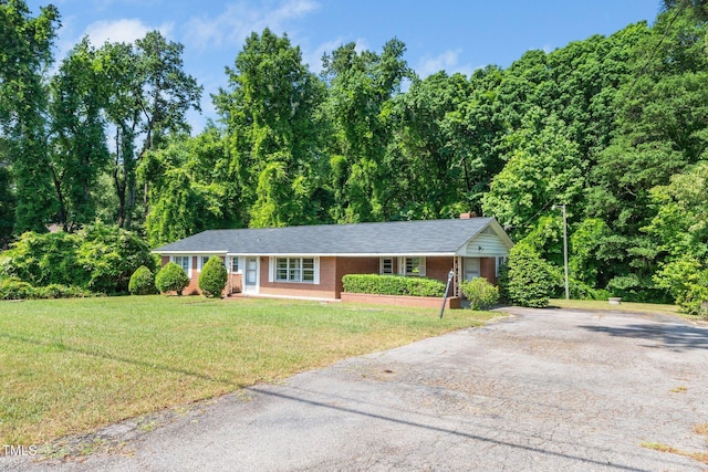 single story home with driveway, brick siding, and a front yard