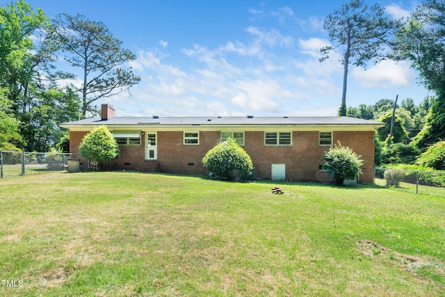 back of property featuring brick siding, a fenced backyard, a yard, and crawl space