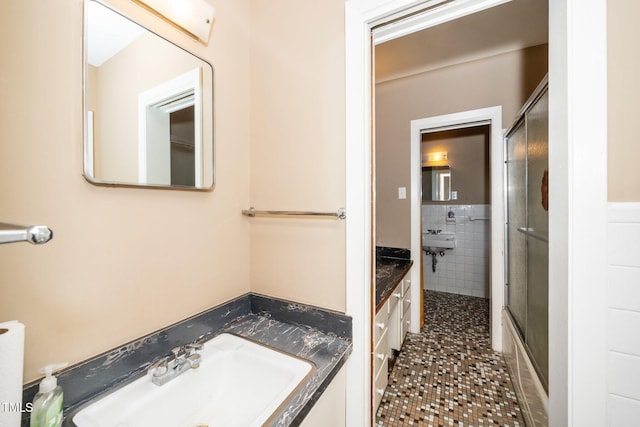 bathroom featuring an enclosed shower, vanity, tile patterned floors, and tile walls