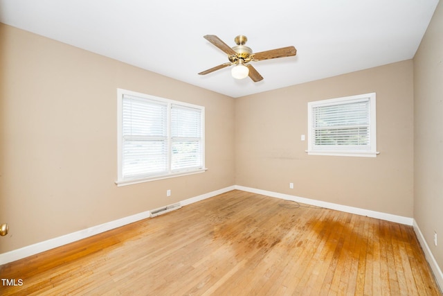 empty room with baseboards, plenty of natural light, light wood-type flooring, and visible vents