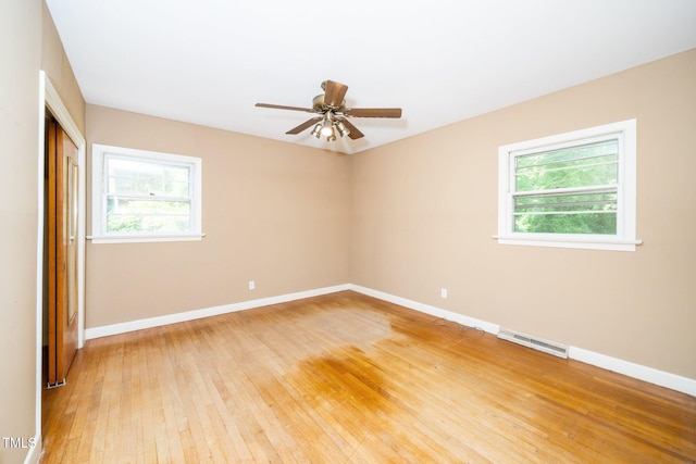 empty room featuring light wood-type flooring, a ceiling fan, baseboards, and visible vents