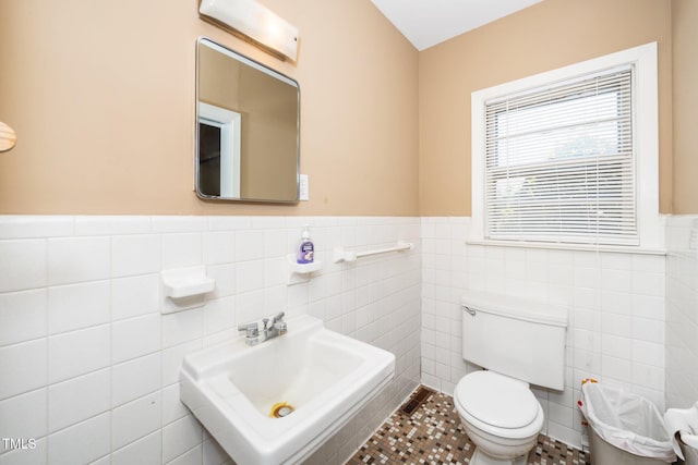 bathroom featuring a sink, tile walls, wainscoting, and toilet