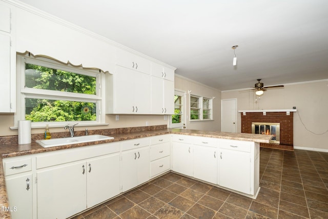 kitchen featuring a sink, ceiling fan, a peninsula, and a healthy amount of sunlight