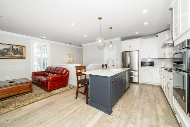 kitchen with crown molding, appliances with stainless steel finishes, a sink, wall chimney exhaust hood, and light wood-type flooring