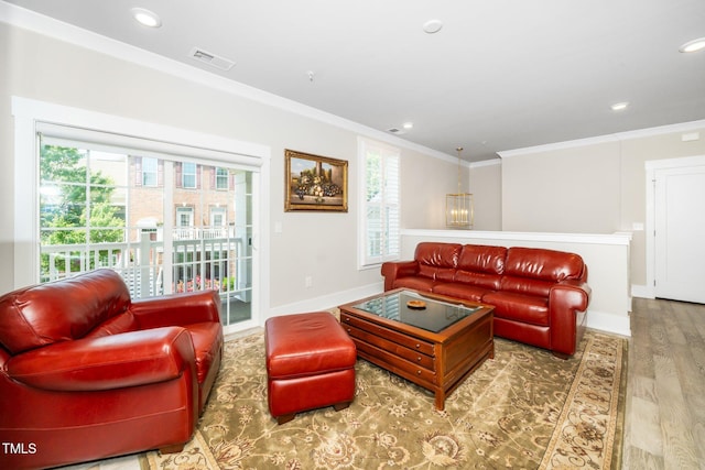 living room with crown molding, a healthy amount of sunlight, wood finished floors, and visible vents