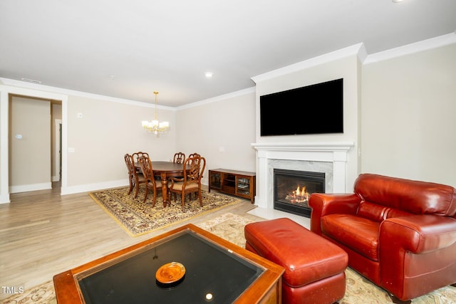 living area with crown molding, a high end fireplace, baseboards, light wood finished floors, and a notable chandelier