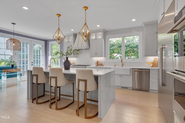 kitchen featuring a sink, dishwasher, a wealth of natural light, and custom exhaust hood