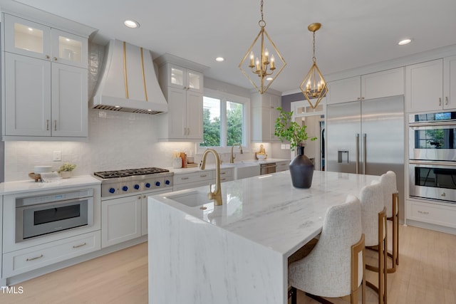kitchen featuring decorative backsplash, a sink, custom exhaust hood, an inviting chandelier, and stainless steel appliances
