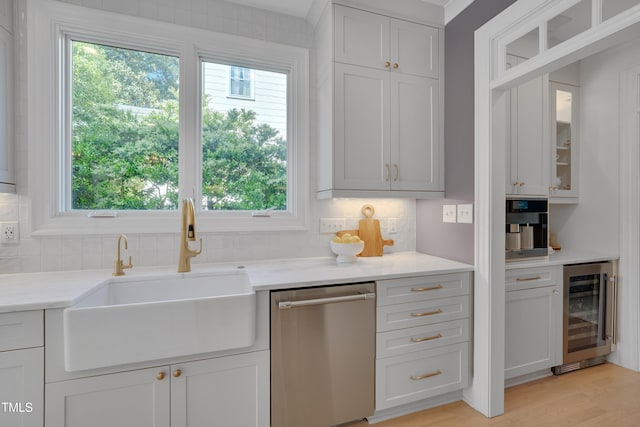 kitchen with glass insert cabinets, beverage cooler, tasteful backsplash, a sink, and dishwasher