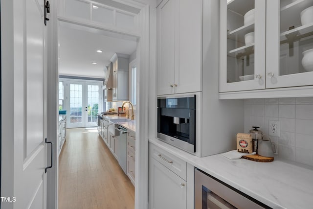 bar featuring french doors, tasteful backsplash, light wood-type flooring, a sink, and wine cooler
