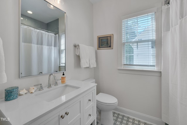 bathroom featuring vanity, baseboards, toilet, and a wealth of natural light