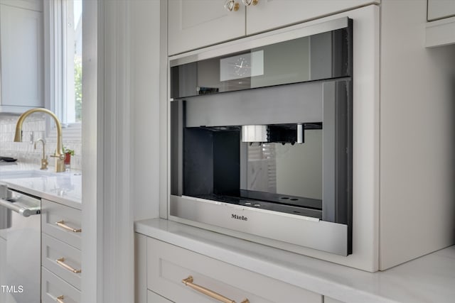 details with light countertops, decorative backsplash, white cabinets, and a sink