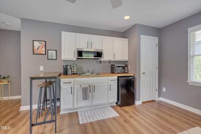 kitchen with light wood-style floors, baseboards, stainless steel microwave, and fridge
