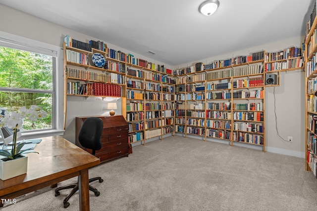 home office featuring carpet flooring, wall of books, and a wealth of natural light