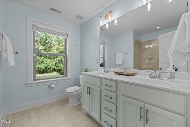 bathroom featuring a sink, baseboards, a tile shower, and visible vents
