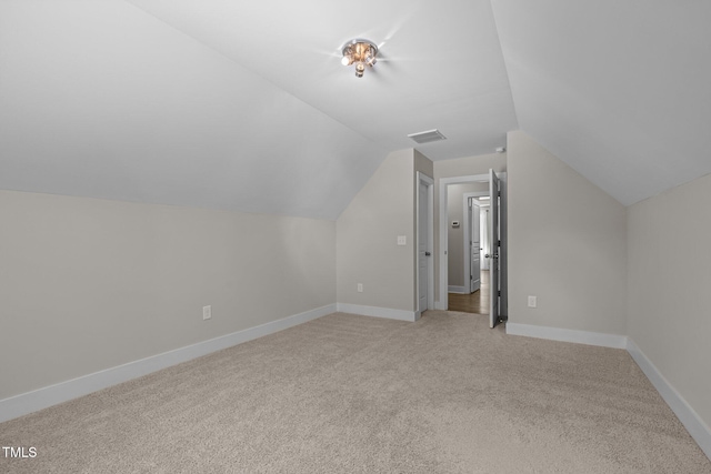 bonus room featuring visible vents, baseboards, vaulted ceiling, and light carpet