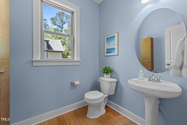 half bath featuring baseboards, wood finished floors, and toilet