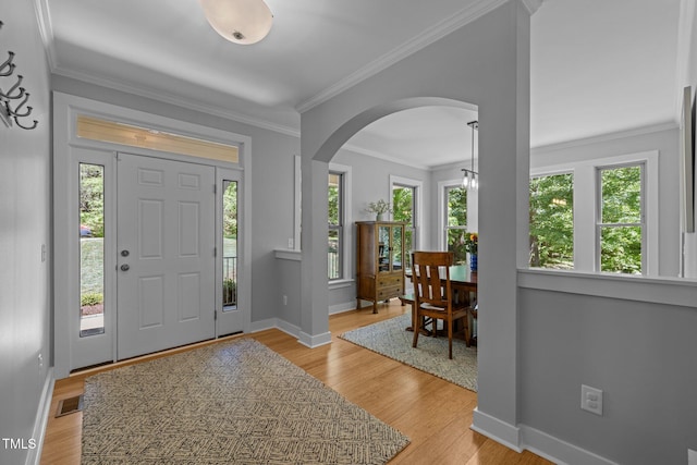 foyer entrance with arched walkways, baseboards, and a wealth of natural light