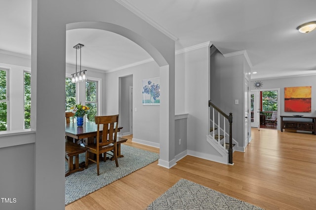 dining room featuring baseboards, arched walkways, wood finished floors, and a healthy amount of sunlight