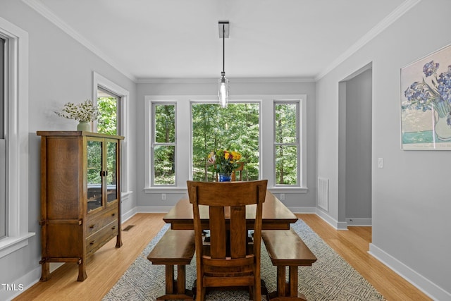 dining room with crown molding, light wood-style flooring, baseboards, and visible vents