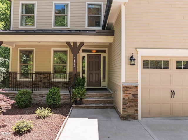 entrance to property with a garage, a porch, driveway, and stone siding