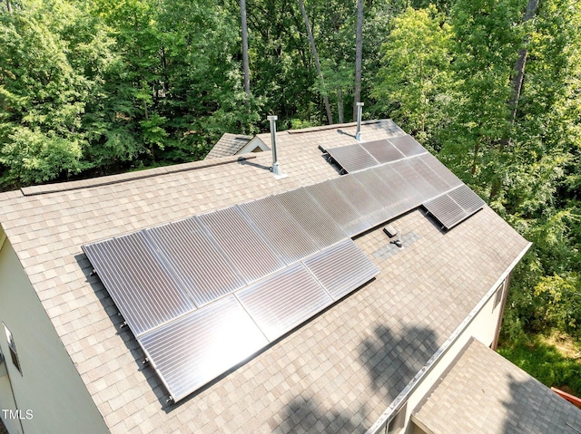 details featuring a view of trees and roof with shingles